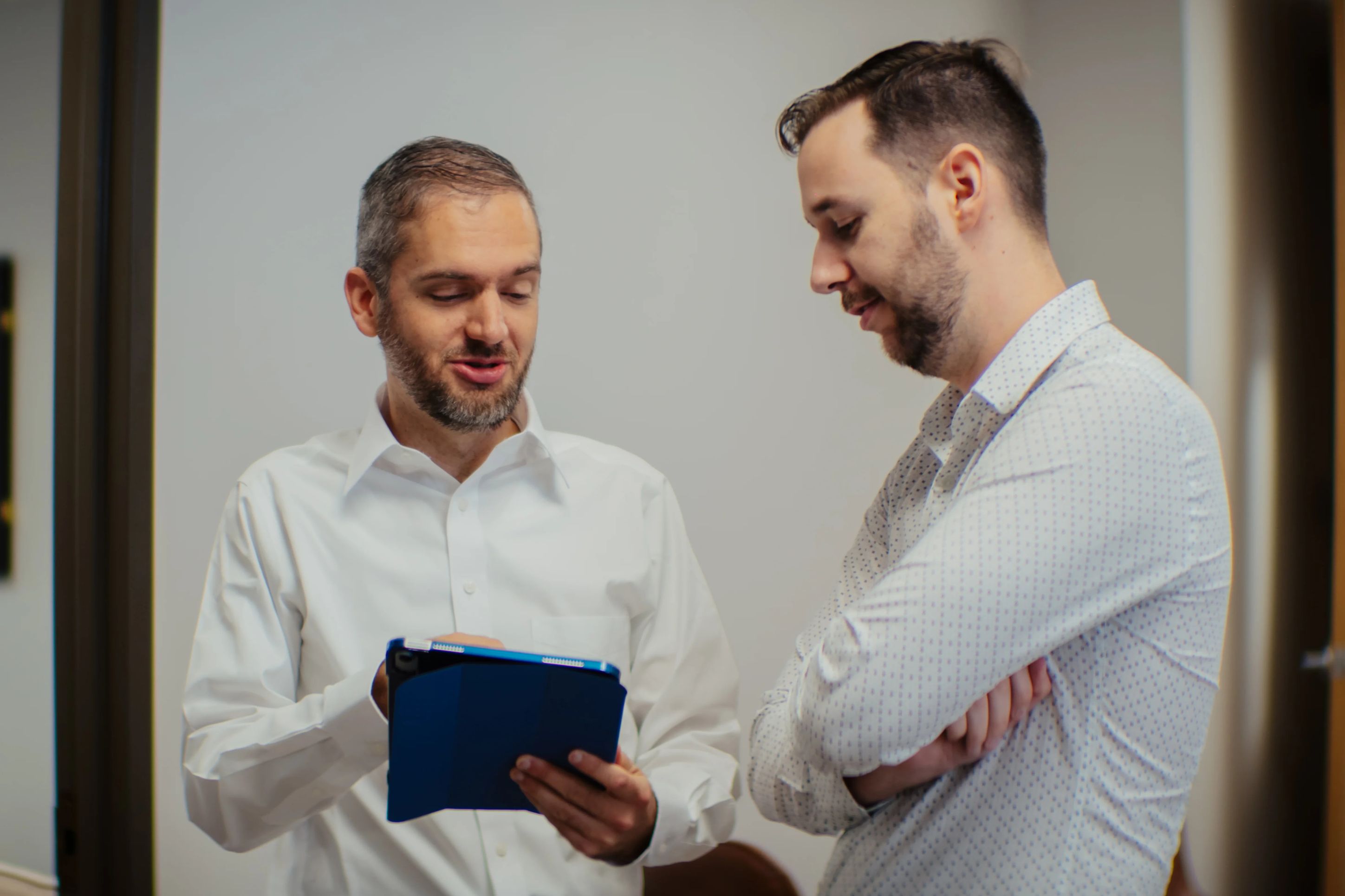 Two consultants reviewing data on a tablet in the hallway